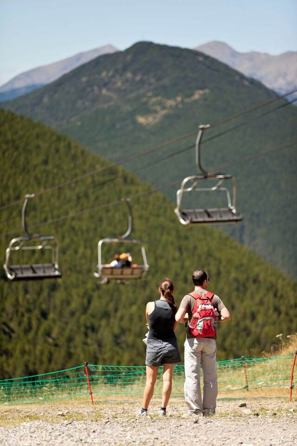 Pareja contemplando la montaña en Andorra en verano junto a un telesilla